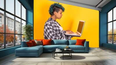 young afro american girl isolated on yellow background with laptop Wall mural