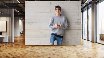 young male teenager with mobile phone on city street Wall mural