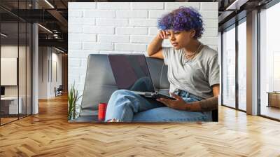 young woman at home with laptop sitting on the living room sofa Wall mural