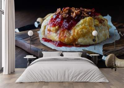 Puff pastry wrapped brie topped with cranberry sauce and bacon, ready to be cut into. Wall mural