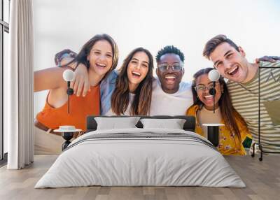 Low angle view of a happy group of multiracial friends looking at camera, enjoying outdoors. Multiethnic cheerful young people Wall mural