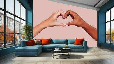 Close up of black and white female hands in heart shape, interracial friendship. Multiracial hands over beige background at studio. Peace and love concept. Wall mural