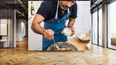 Latin cook cooking octopus in the kitchen. Chef preparing food for a private dinner at home. Gourmet, delicatessen meal. Wall mural