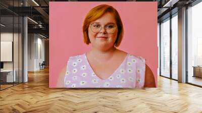 headshot of smiling young redhead woman with short hair and eyeglasses looking at camera in studio over pink background Wall mural