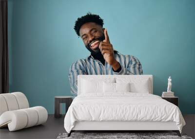 portrait of a black young african american man laughing with beard and mustache on a blue background Wall mural