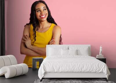 Portrait of a confident young woman with long black curly hair smiling with arms crossed and looking up Wall mural