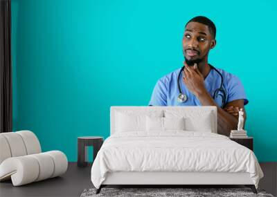 Portrait of a friendly male doctor or nurse wearing blue scrubs uniform thinking and looking to side at copy space Wall mural