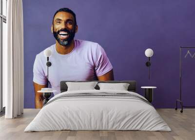 portrait of a handsome smiling man with beard and mustache purple shirt on a gray looking away at copy space background studio Wall mural