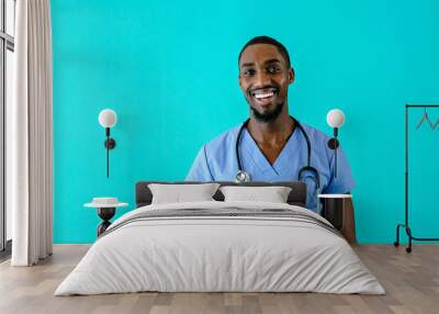 Portrait of a happy male doctor or nurse wearing blue scrubs uniform and smiling, isolated on blue studio background Wall mural