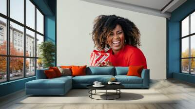 Portrait of a happy mid woman laughing and holding red Christmas gift box Wall mural