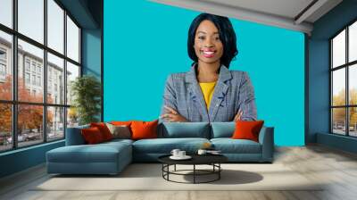 Portrait of a  happy smiling young woman in business jacket with arms crossed isolated on blue Wall mural