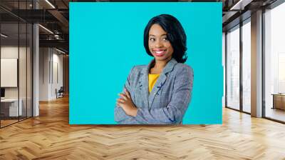 Portrait of a  happy smiling young woman in business jacket with arms crossed looking to side isolated on blue Wall mural