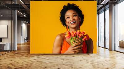 Portrait of a happy smiling young woman with orange tulips bouquet looking up Wall mural