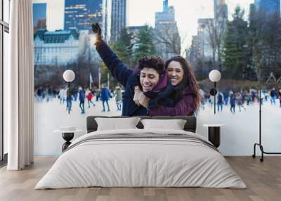 Portrait of a happy young couple smiling, hugging and having fun while ice skating outside in Central Park, NYC Wall mural