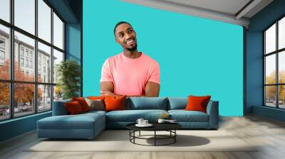 Portrait of a happy young man smiling with arms crossed and looking up at blue studio copy space Wall mural