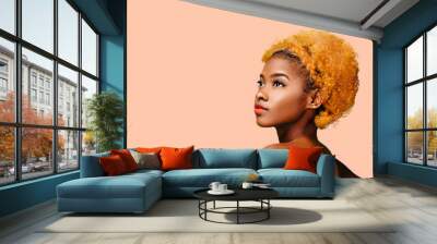 Portrait of a lovely young girl with bleached curly hair looking up, isolated on a peach background	 Wall mural