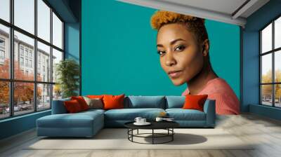 Portrait of a serious young african female with cool short hair looking at camera, against studio background Wall mural