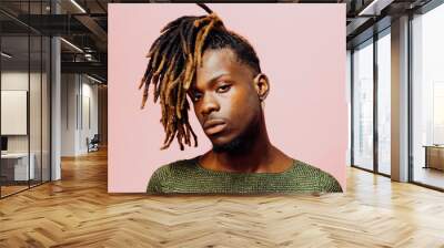 Portrait of a serious  young man in with cool dreadlocks hairstyle, isolated on pink. Wall mural