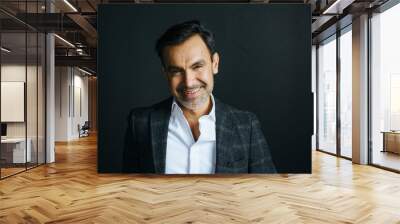 Portrait of a stylish latin hispanic man smiling,  on black studio background Wall mural