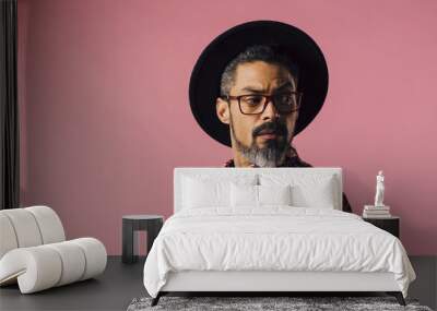 Portrait of a very cool man with tilted hat looking to side, isolated on pink studio background Wall mural