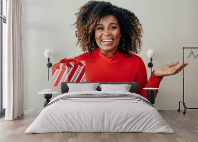 Portrait of a very excited woman holding red Christmas gift box gesturing with hand Wall mural