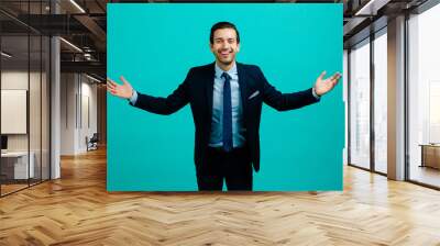 Portrait of a young entrepreneur business man smiling with arms open,  isolated on blue studio background Wall mural