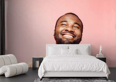 Portrait of a young man with big smile looking up, isolated on colorful background Wall mural