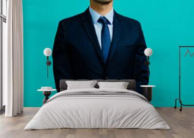 Serious, portrait of a young entrepreneur business man holding his hands together, isolated on blue studio background Wall mural