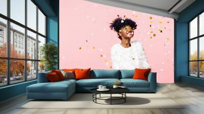 Smiling woman looking up at confetti falling Wall mural