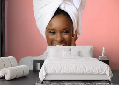 Young beautiful woman in bathrobe with white towel on head posing on pink background Wall mural