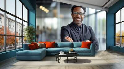 Mid adult African American Black businessman arms crossed smiling looking at camera in modern office wearing eyeglasses Wall mural