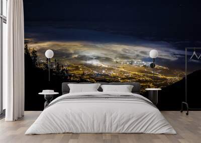 Night image from the mountain of the north coast of Tenerife with a beautiful view of the city lights and the glowing clouds below Wall mural