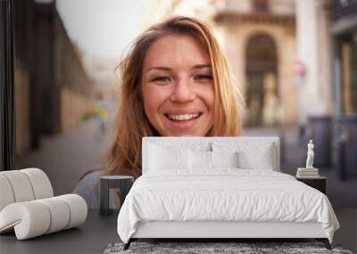 Close up portrait of cheerful attractive young Caucasian woman happy smiling face on street. Female people with joyful expression looking at camera outdoor. Blonde gen z girl posing natural for photo Wall mural