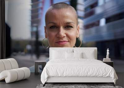 Close-up portrait of empowered middle-aged Caucasian business woman looking confident at camera. Formal attractive female posing elegant outdoors. Shaved head white person with successful expression Wall mural