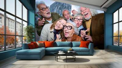 Funny flash portrait of group seniors Caucasian people posing making gestures together outdoors. Older friends with gray hair looking joyful at camera dusk in city. Lifestyle happy matures partners Wall mural