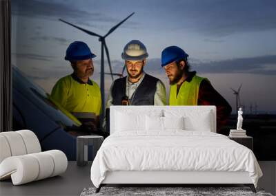 Group of engineers in discussed the plan for the maintenance of wind turbines working with a laptop in a field wind turbines power station. Renewable and clean energy concept, sustainable future Wall mural