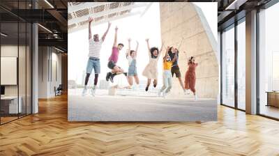 Group of happy multiethnic friends having fun. Young students jumping outside the university. Wall mural