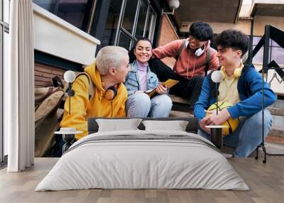 Group of happy young diverse colleagues talking and having fun together outdoors on college campus. Happy teenage students talking outside high school building. People in their leisure time. Wall mural