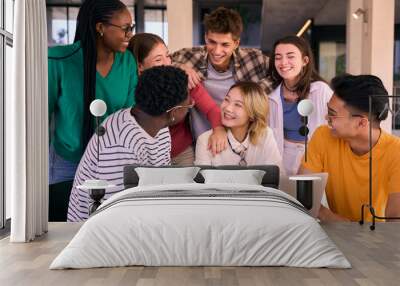 Group of young university students smiling using laptop computer at class room table on campus. Cheerful multiracial people working together on project in faculty. Online education in generation z Wall mural