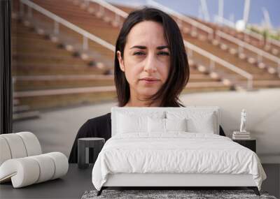 Outdoor portrait of a Hispanic woman looking at the camera with a serious face. Close-up of a serious female face. Concept of people and emotions. Wall mural