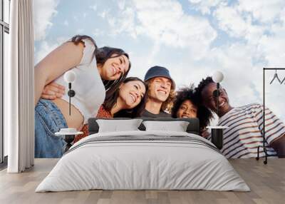 Portrait with copy space from a low angle of a group of smiling young multiethnic people. In the background a beautiful sky with clouds. Wall mural