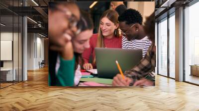 Selective focus on smiling young girl and a black guy studying together with workbooks and using laptop in the classroom. Group of academic multiracial people working together on the faculty campus Wall mural