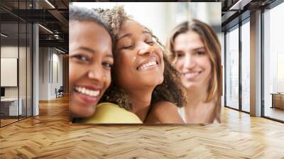 Selfie of three happy young multi-ethnic beautiful girls posing smiling looking at camera indoors. Cheerful people together enjoying a day at leisure. Positive friendship multiracial women relations. Wall mural