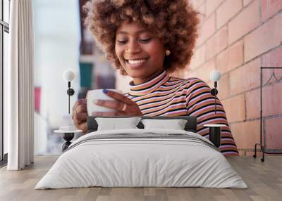 Smiling young black woman with afro hair looking at mug on balcony at home. Cheerful African American girl holding cup of hot drink outdoors. Happy generation z beautiful female enjoying domestic life Wall mural