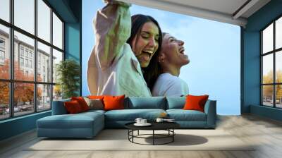 Two excited young Caucasian friends hanging out dancing party in evening having fun at weekend. Happy beautiful people enjoying leisure time outdoor. Attractive gen z women celebrating summer night. Wall mural