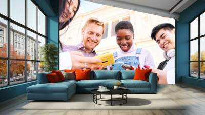 Vertical photo of Group of multirracial friends using mobile cell together outdoors having fun watching smart phone. Diversity People Meeting Relaxing Connection Communication Community Concept.  Wall mural