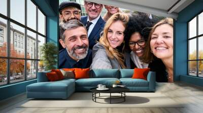 Vertical selfie of a cheerful team of diverse business people in formal suit looking smiling at camera gathered outside the work building. Positive emotion team work celebrating success together Wall mural