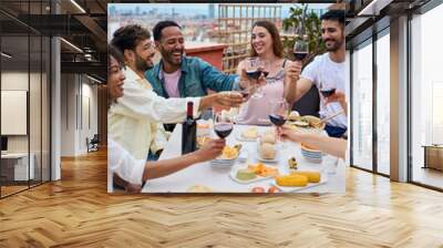 Vertical. Group of happy young people toasting red wine and celebrating meal on rooftop. Multiracial millennial friends together drinking alcoholic beverages outdoor enjoying lunch on holidays Wall mural