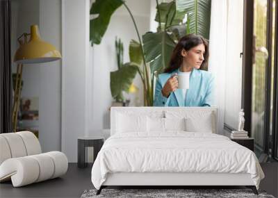 Young business woman enjoying relaxing with her morning coffee or tea, looking out the window. Beautiful latina woman getting inspired on break from work at the office. Wall mural