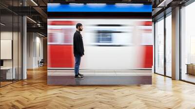 Young man on his side with a mask on the subway platform. The movement of the subway caravan in the background. Copy space. Wall mural